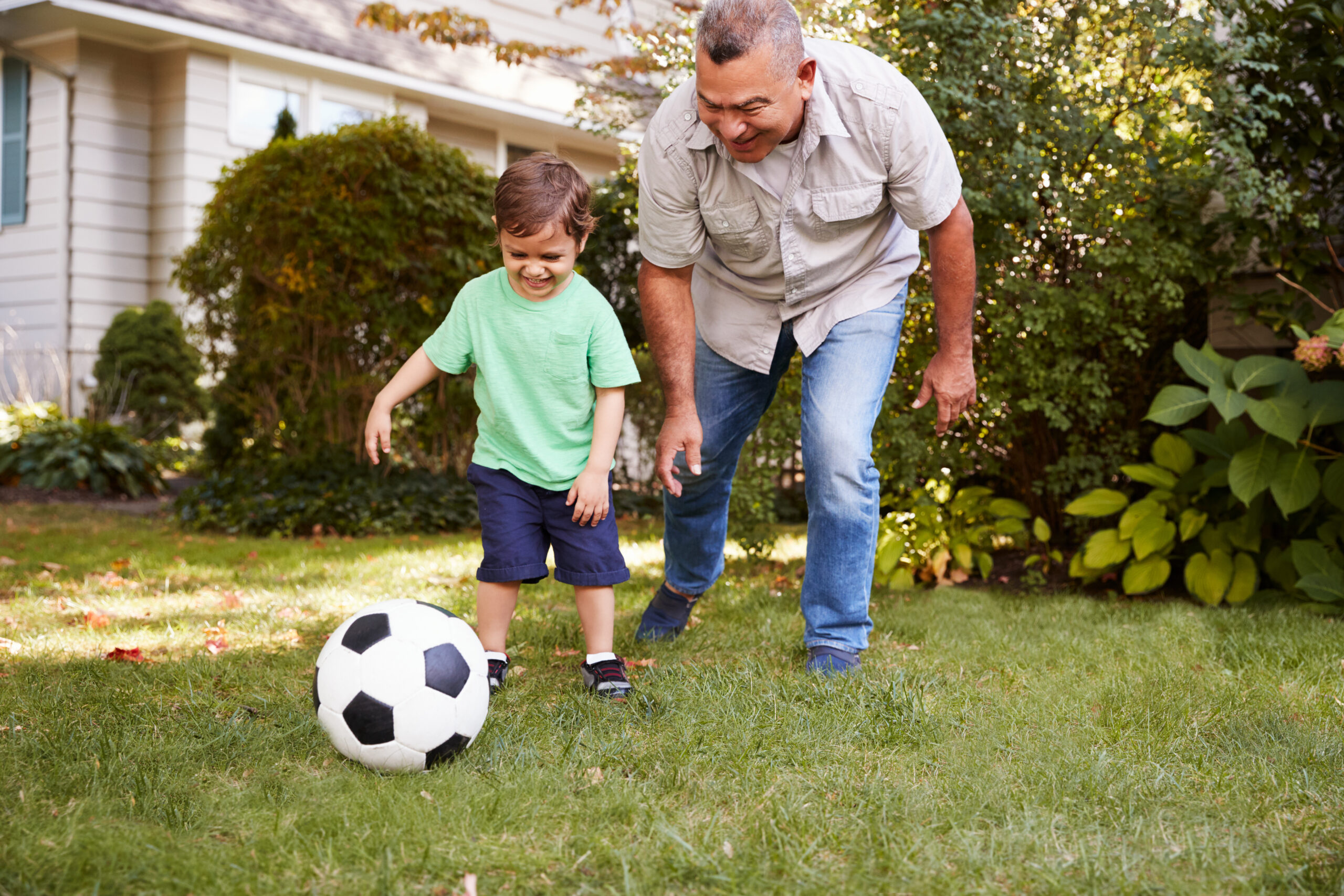 Father and son playing soccer outdoors